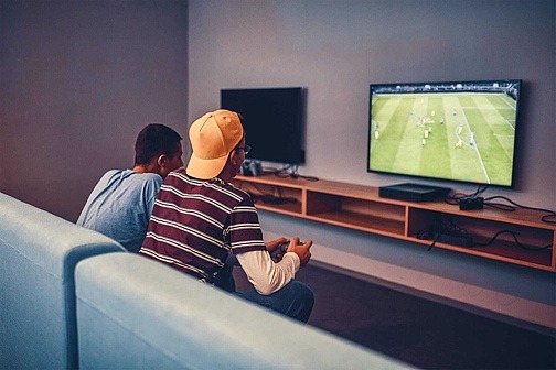 spannende Videospiele Zwei Jungen sitzen auf Sofa und spielen Videospiel gegeneinander